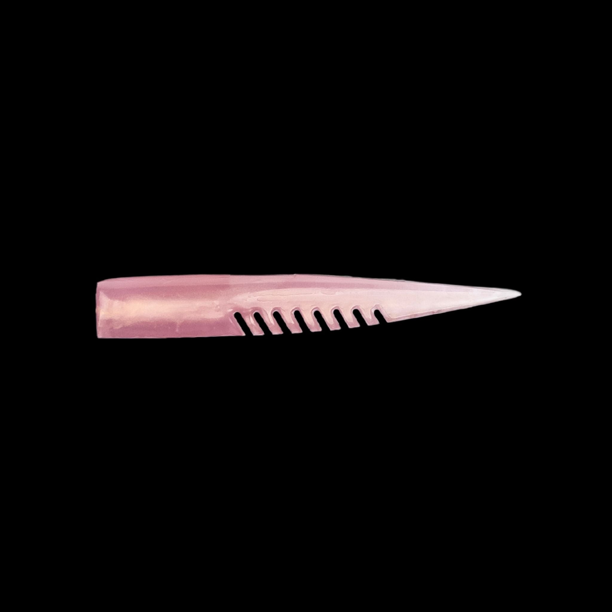 pink fishing lure with a comb-like texture on a black background