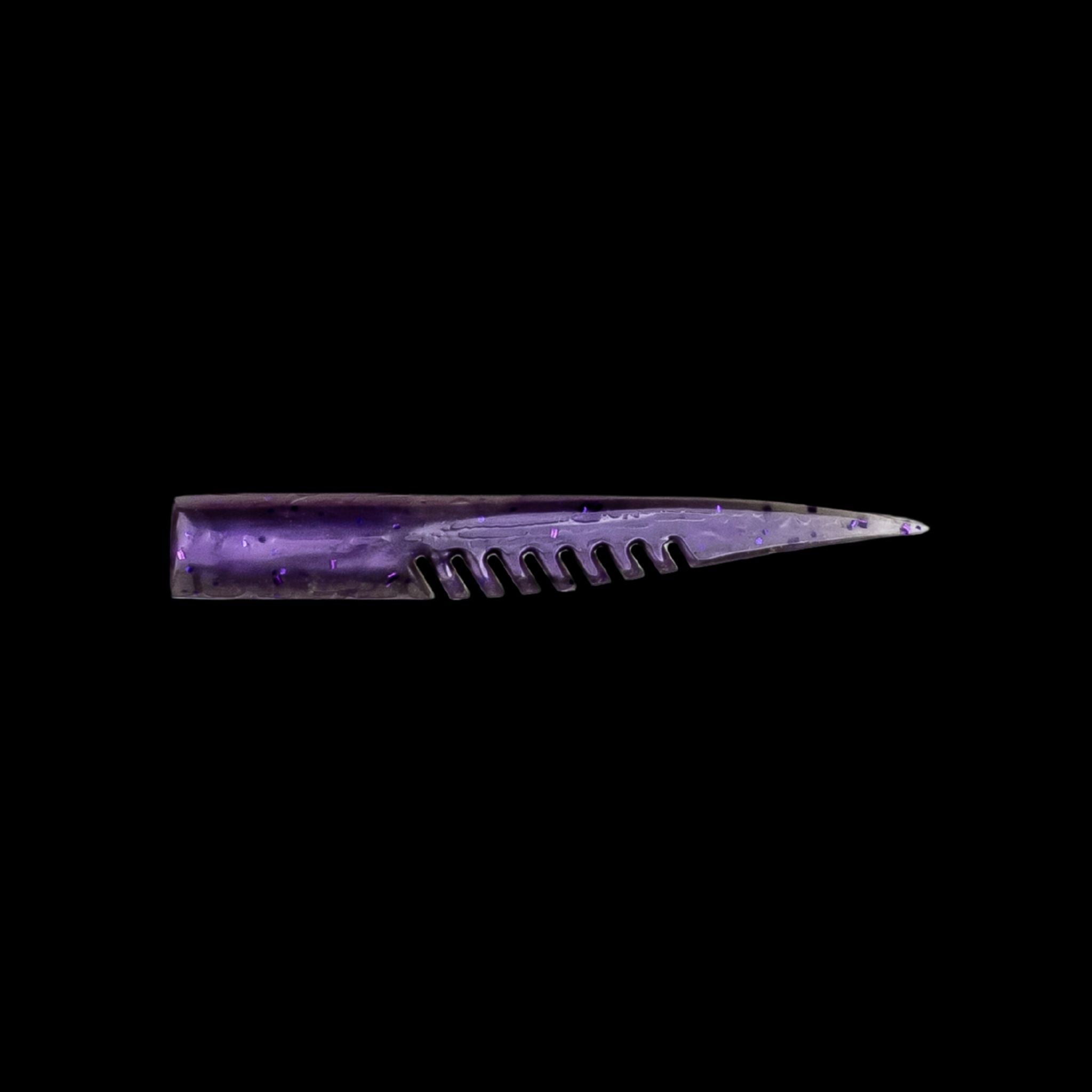 purple fishing lure with a comb-like texture on a black background