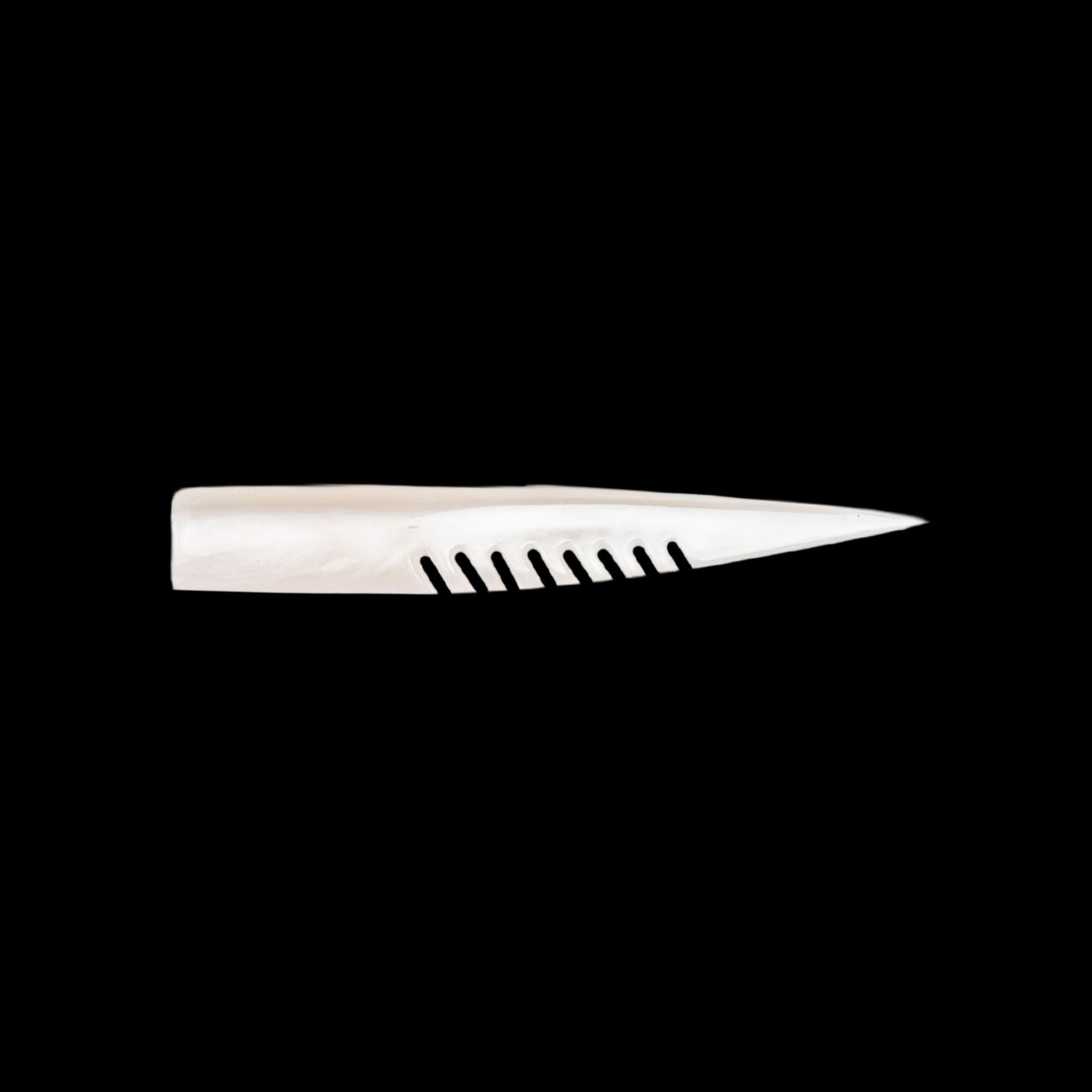 white fishing lure with a comb-like texture on a black background