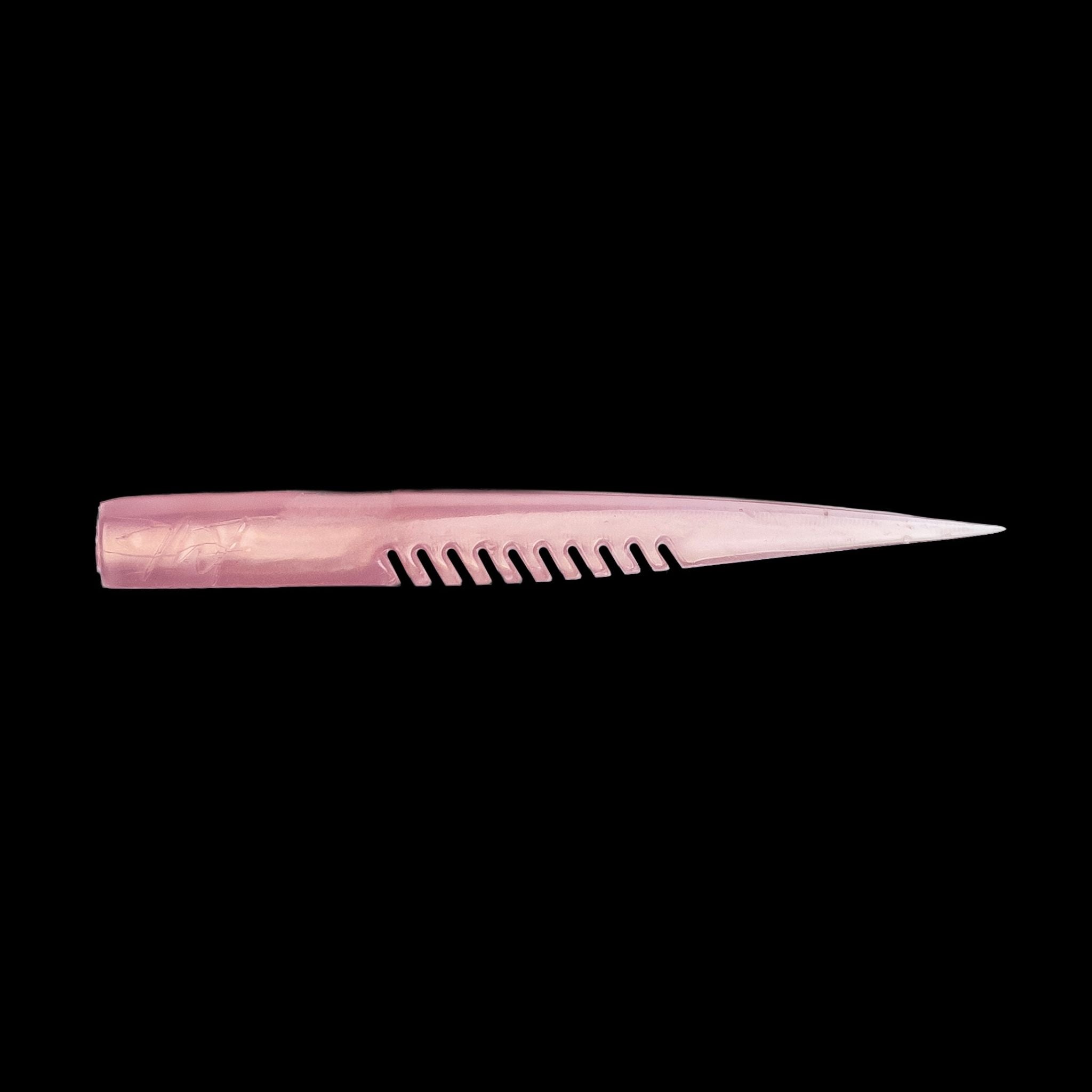 pink fishing lure with a comb-like texture on a black background