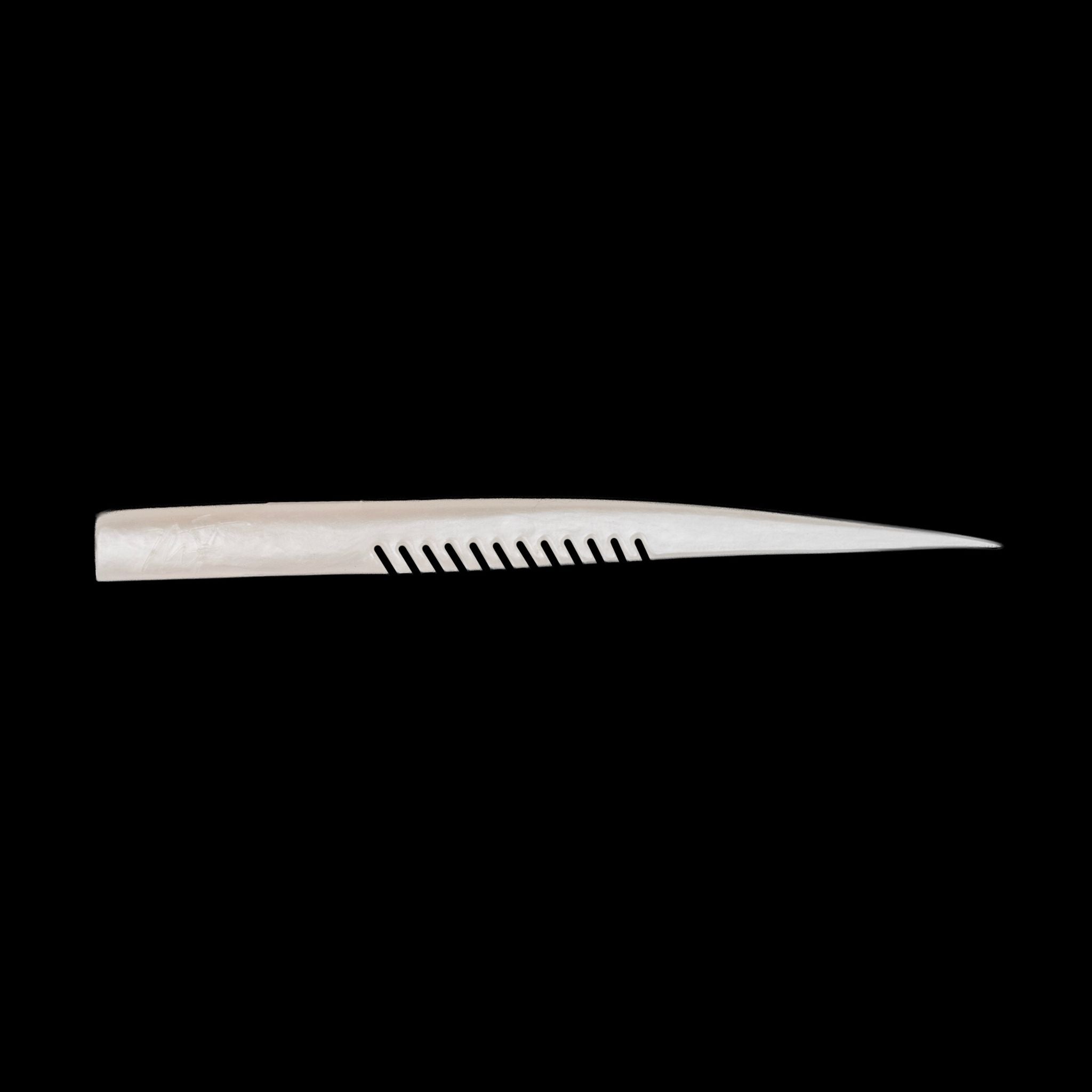 white fishing lure with a comb-like texture on a black background